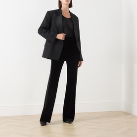 Model wearing Max Mara Studio black cotton-elastane trousers with wide-leg silhouette, styled with matching black blazer and top.