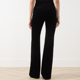 Model wearing Max Mara Studio black velvet flared trousers, rear view, with wide-leg silhouette and high-rise waist.