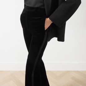Model wearing Max Mara Studio black velvet flared trousers with satin side stripe, styled with a black satin blazer.