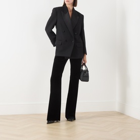 Model wearing Max Mara Studio black cotton-elastane flared trousers, styled with a black double-breasted blazer and small black handbag.