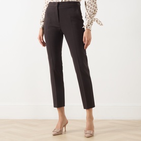 Model wearing Max Mara Main dark brown slim-leg tailored wool trousers, styled with a floral blouse and nude heels.