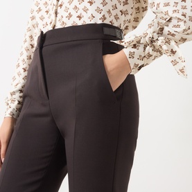Model wearing Max Mara Main dark brown virgin wool slim-fit trousers with belt detail, styled with a printed blouse.