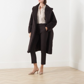 Model wearing Max Mara Main Dark Brown virgin wool slim-leg trousers, styled with a longline coat and printed blouse.