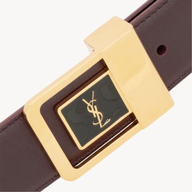 Saint Laurent red tan leather belt with oversized gold-tone buckle featuring black YSL monogram detail, close-up view