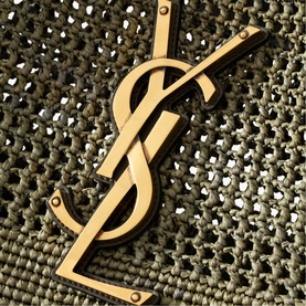 Saint Laurent light musk bag with oversized gold-tone YSL monogram hardware detail on textured fabric surface