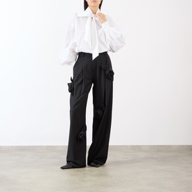 Model wearing MeiMeij Nero wide-leg trousers with bow-detail pockets, styled with a white tie-neck blouse.