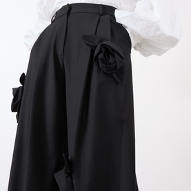 Model wearing MeiMeij Nero wide-leg wool trousers with 3D rose appliqu&eacute; detail at hip, styled with white ruffled blouse.
