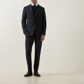 Model wearing Tiger of Sweden Dark Ink suit jacket with matching trousers, white shirt, black knitwear, and black leather shoes.