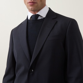 Model wearing Tiger of Sweden Dark Ink suit jacket, styled with a navy crew-neck knitwear and dark tie, single-button detail visible.