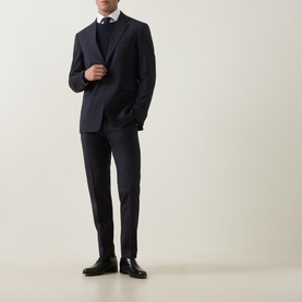 Model wearing Tiger of Sweden Dark Ink suit jacket with matching trousers, white shirt, dark tie, and black leather Oxford shoes.