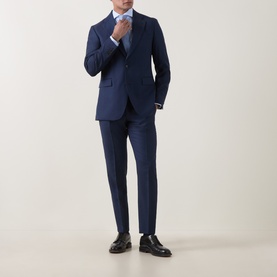 Model wearing Tiger of Sweden sea blue wool suit jacket with matching trousers, light blue shirt, tie, and black leather shoes