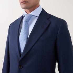 Model wearing Tiger of Sweden Suit Jacket in Sea navy, styled with a light blue shirt and patterned tie, single-button detail visible.