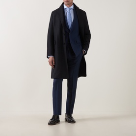 Model wearing Tiger of Sweden sea blue wool suit jacket, styled with black overcoat, light blue shirt and black loafers