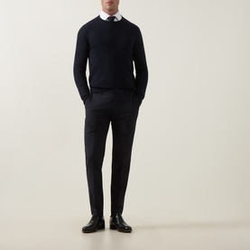 Model wearing Tiger Sweden Dark Ink suit trousers, styled with a navy crew-neck sweater, white shirt, and black leather shoes.
