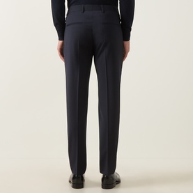 Model wearing Tiger of Sweden Dark Ink suit trousers, rear view, styled with navy shirt and black leather loafers.