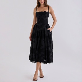 Model wearing House of CB black lace midi dress with spaghetti straps, full skirt and side pockets, styled with black heeled sandals