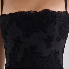 Model wearing House of CB black lace appliqu&eacute; corset top with scalloped neckline and thin straps, close-up detail shot