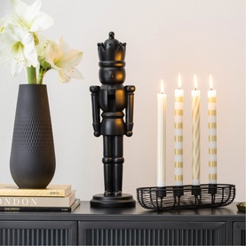 Villeroy & Boch black nutcracker figure styled with dark vase, white flowers, and lit candles on sideboard