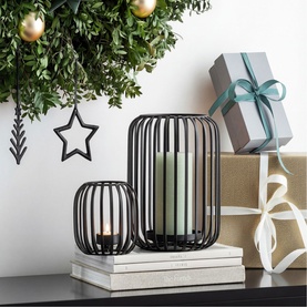 Villeroy & Boch black wire lantern candle holders in two sizes, styled with greenery, star ornaments and wrapped gifts