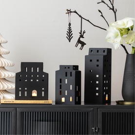 Villeroy & Boch black metal house-shaped tealight holders in three sizes, styled with white amaryllis and Christmas decorations on dark cabinet