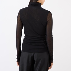 Model wearing MeiMeij Nero long-sleeve turtleneck top in sheer black polyamide, styled with dark trousers, rear view.