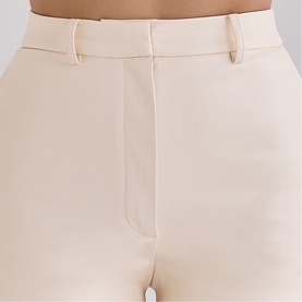 Model wearing House of CB ivory tailored trousers, close-up of waistband and belt loops detail