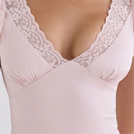 Model wearing House of CB Crystal Pink bodysuit with V-neck and delicate lace trim detail at neckline.