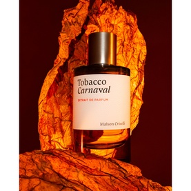 Maison Crivelli Tobacco Carnaval Extrait de Parfum glass bottle with dark cap, styled on textured amber rock surface