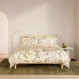 Sheridan Cream Duvet Set with floral print, styled on a bed with matching pillowcases in a warm neutral bedroom setting