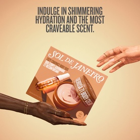 Sol De Janeiro Cozy Cravings Body Duo Gift Set held between two hands, featuring body cream and a small serum bottle on warm beige background