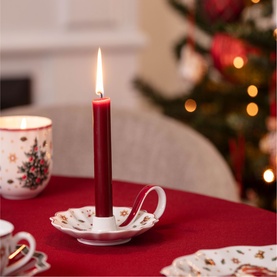 Villeroy & Boch white porcelain candle holder with festive motifs, holding a lit red taper candle, styled on a red Christmas table
