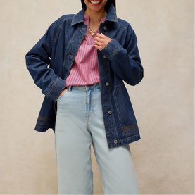 Model wearing White Stuff mid denim oversized jacket, styled with a pink stripe shirt and light wash wide-leg jeans