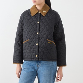 Model wearing Barbour black quilted jacket with tan corduroy collar and gold-tone buttons, styled with light blue jeans.