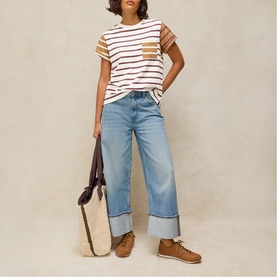 Model wearing White Stuff ivory multi stripe t-shirt with wide-leg light wash jeans, styled with brown trainers and a canvas tote bag.