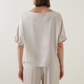 Model wearing FeeG Champagne Top, back view, with elasticated short sleeves and relaxed fit, styled with matching wide-leg trousers.