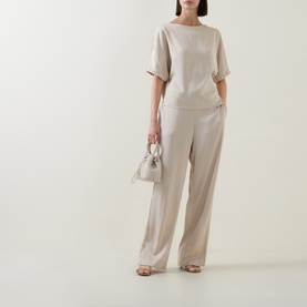Model wearing FeeG Champagne top with matching wide-leg trousers, styled with a white mini bag and strappy heeled sandals.