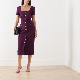 Model wearing FeeG plum midi dress with short sleeves, square neckline and gold button-front detail, styled with pink heeled sandals and black clutch