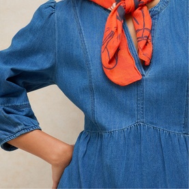 Model wearing White Stuff mid denim dress with puff sleeves and V-neckline, styled with an orange printed neck scarf.