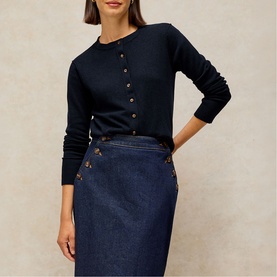 Model wearing White Stuff dark navy fine knit cardigan with gold buttons, styled with a dark denim pencil skirt with button detail.