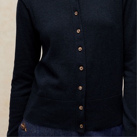 Model wearing White Stuff dark navy button-front cardigan with round neck and front pockets, styled over dark denim.