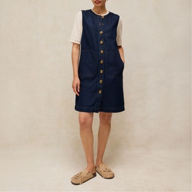 Model wearing White Stuff dark denim sleeveless button-front dress, styled with cream short-sleeve top and tan sandals.