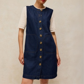 Model wearing White Stuff dark denim sleeveless button-front dress with patch pockets, styled with a white short-sleeve top underneath.