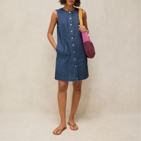 Model wearing White Stuff denim stripe sleeveless mini dress in denim multi, styled with tan flat sandals and carrying a purple bag.