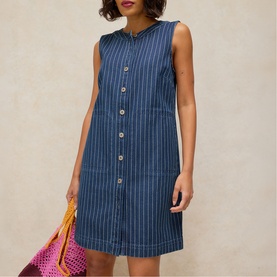 Model wearing White Stuff denim blue pinstripe sleeveless button-through mini dress, styled with a pink woven bag.