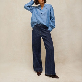 Model wearing White Stuff blue multi spot print relaxed shirt with wide-leg dark indigo jeans and brown heeled ankle boots