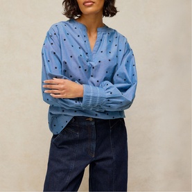 Model wearing White Stuff blue multi spot print blouse with V-neck and long sleeves, styled with dark navy jeans