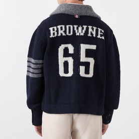 Model wearing Thom Browne navy wool cardigan, rear view showing BROWNE 65 intarsia knit, grey collar, and 4-bar stripe sleeves