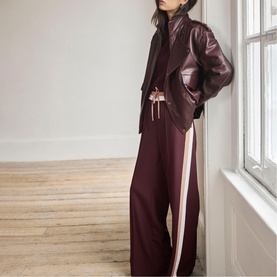Model wearing Mint Velvet red wide-leg trousers with side stripe, styled with a matching red leather jacket