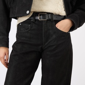 Model wearing Isabel Marant Etoile black jeans, styled with a black leather belt and cream knit top under a black denim jacket.