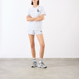 Model wearing Sporty and Rich Heather Gray Navy/Fire Red cotton tee with matching shorts and grey chunky trainers, arms crossed.